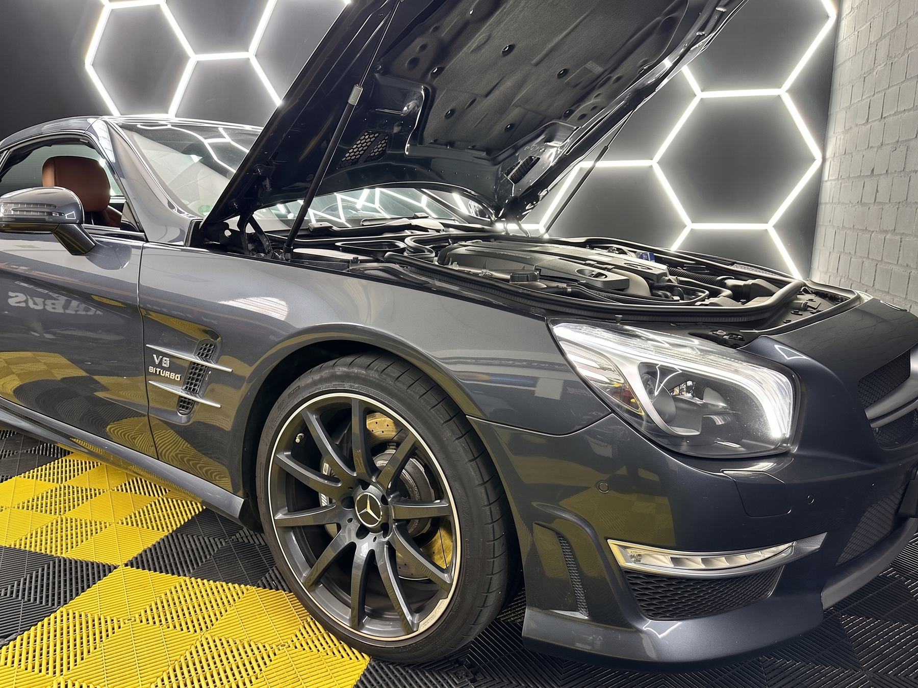 Mercedes-AMG SL 63 mit geöffneter Motorhaube in der Werkstatt von AjPerformance, im Hintergrund die Hexagon-Beleuchtung